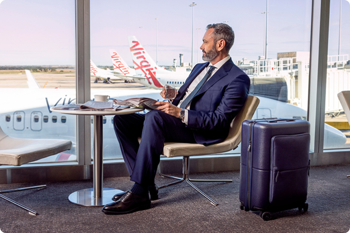 Man at the airport with Virgin Australia plane behind him.