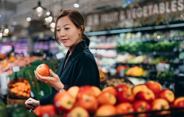 Woman holding an apple at a grocery store