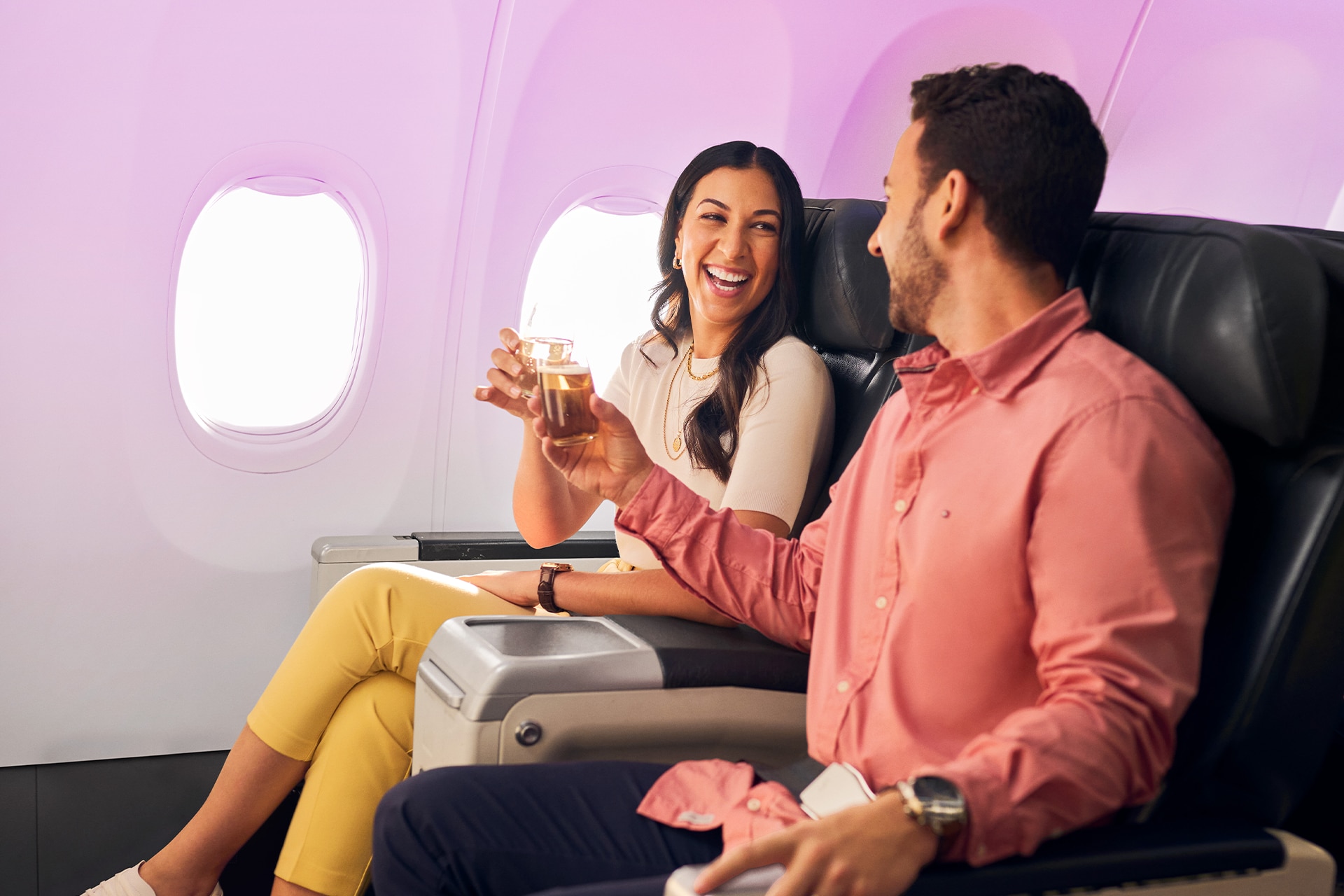 A couple clinking their glasses while seated on a VA flight