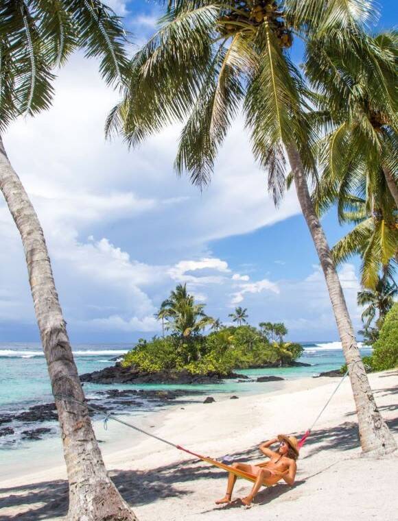 A person lying on a hammock on a beach