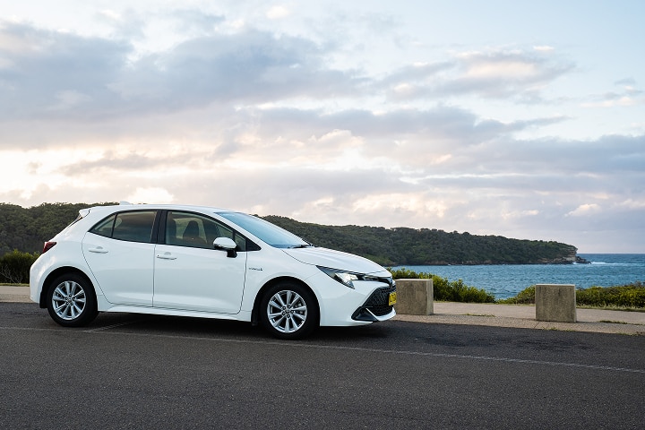 White hatchback car with a beach on the background