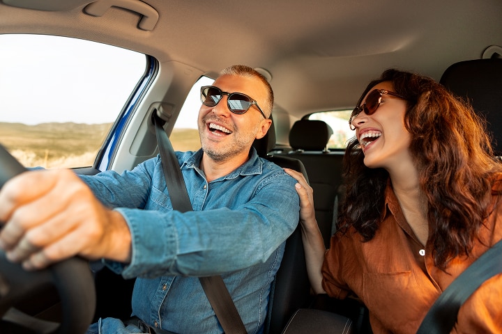 Couple launghing and driving a car