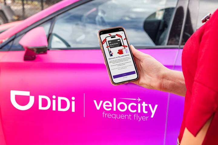 Image of person holding phone in front of car. DiDi. Velocity Frequent Flyer