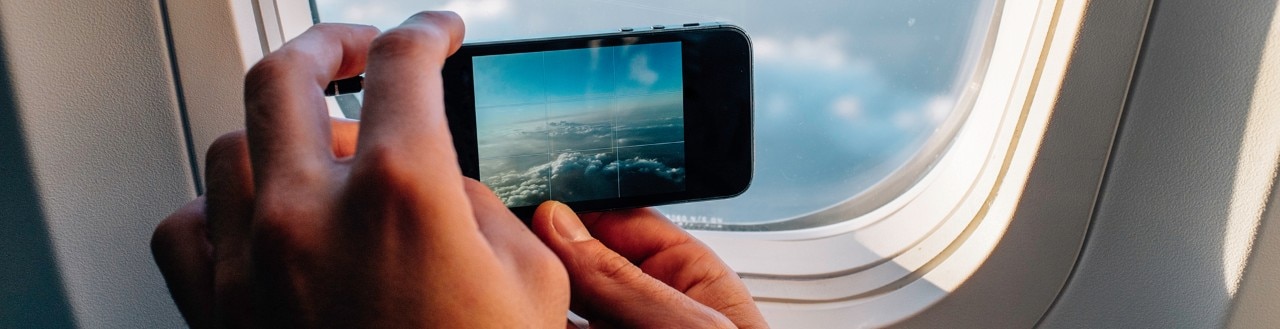 Person using their mobile phone to take a photo out of plane window